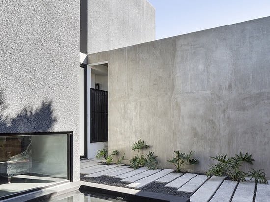 la casa combina diversos volúmenes en concreto negro y gris