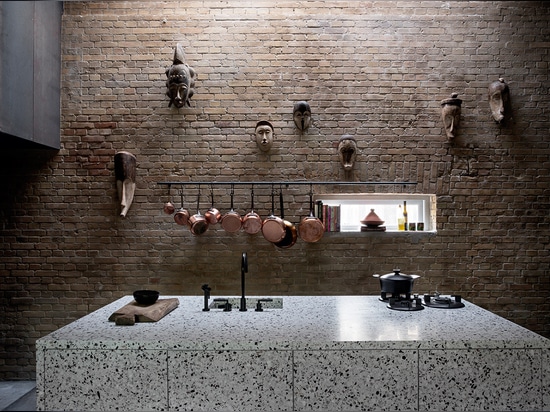 La cocina open-plan ofrece un bloque manchado de la cocina del terrazo diseñado por Thulstrup y las máscaras africanas recogidas por el dueño en el suyo viajan