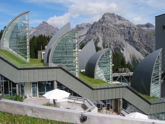 La parte más mayor del nuevo edificio desaparece algo en la montaña.