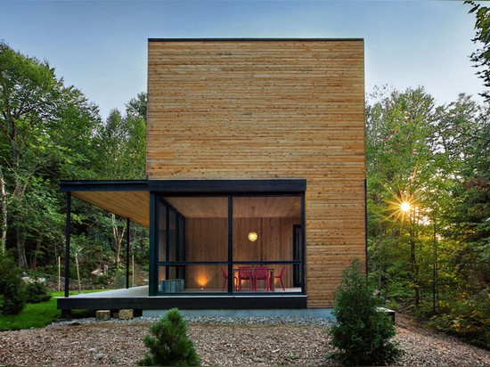 Esta casa revestida de madera está en el país en los árboles