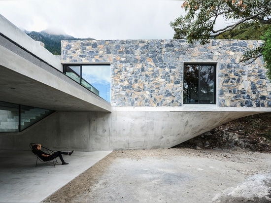 Las cajas de piedra suben en un toldo de bosque en una base concreta esculpida