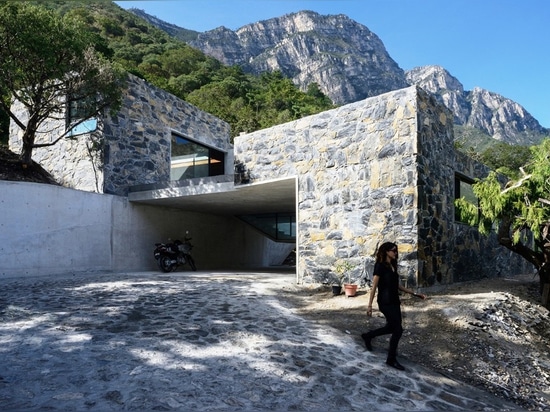 Las cajas de piedra suben en un toldo de bosque en una base concreta esculpida