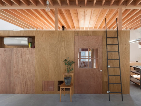 Una escalera aterriza en un escritorio dentro de la casa en Hikone de Tato Architects