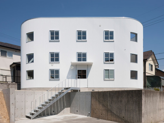 Una escalera aterriza en un escritorio dentro de la casa en Hikone de Tato Architects