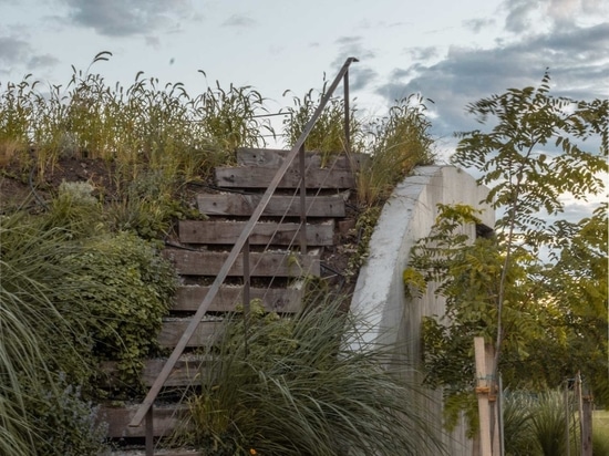 Una casa que surge del suelo formando un jardín de tres niveles